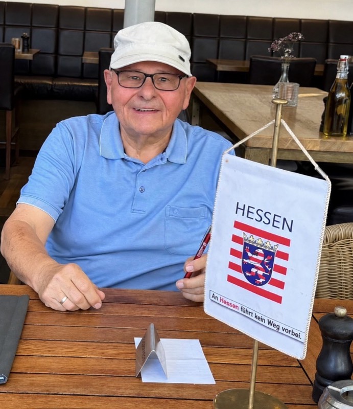Willy Tandler mit einem Hessen-Wimpel am Tisch im Chez Léon